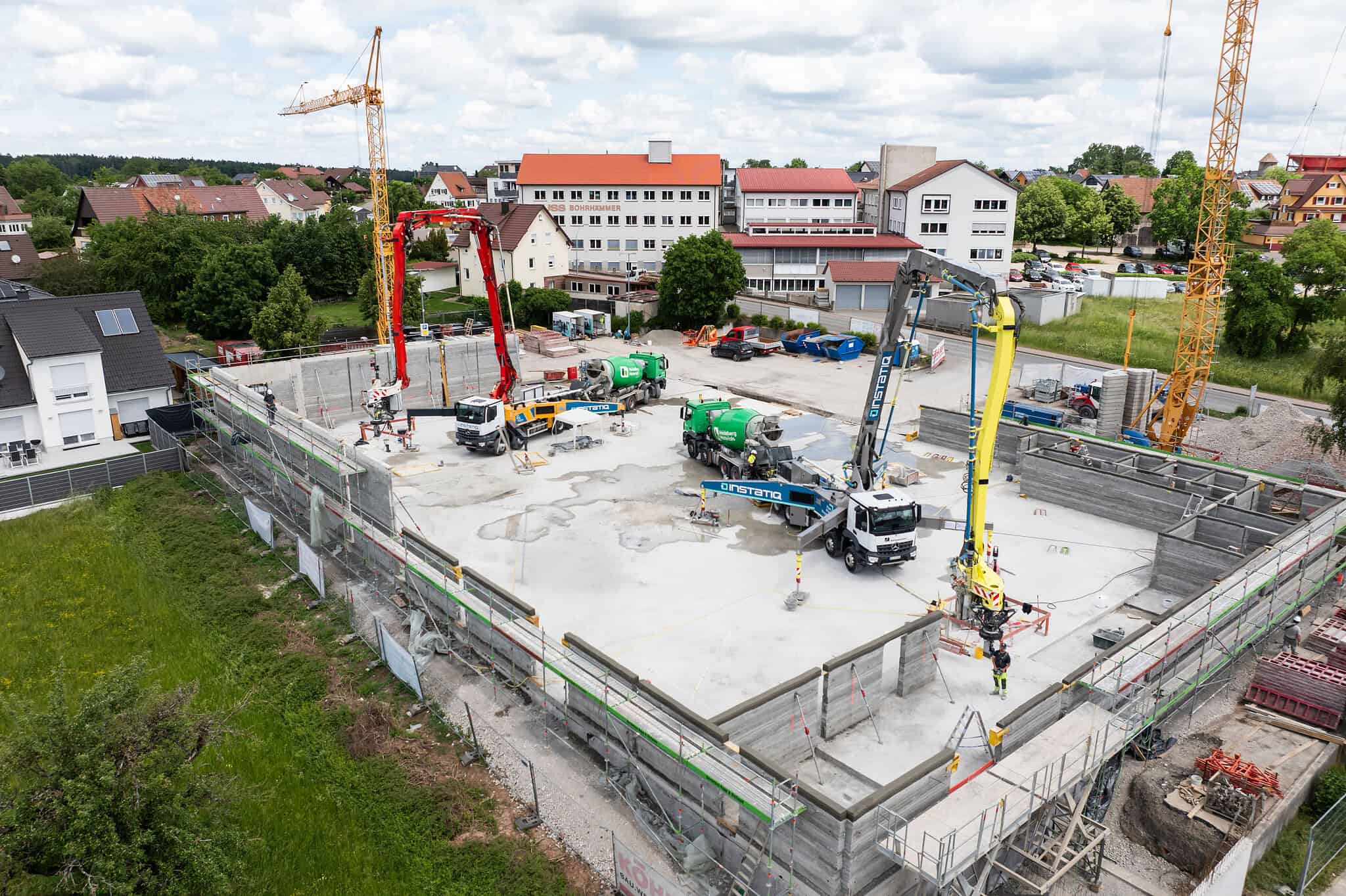Aerial view of INSTATIQ concrete-printing robots working among printed walls on a construction site.