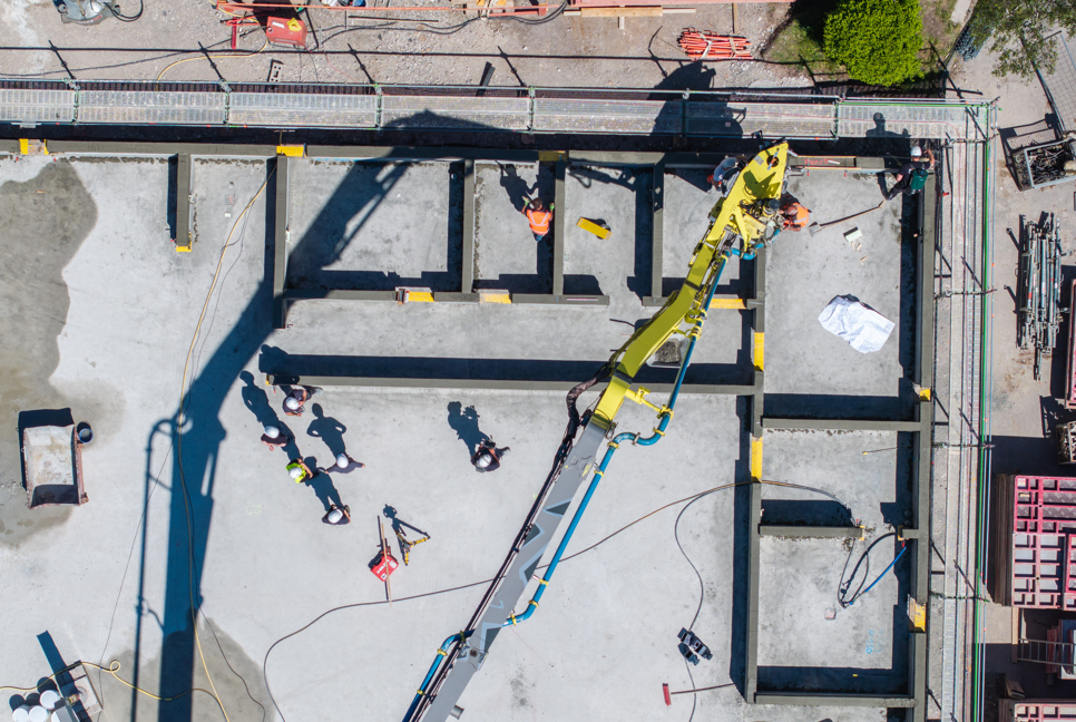 Overhead photograph of an INSTATIQ concrete-printing robot among printed walls and workers.